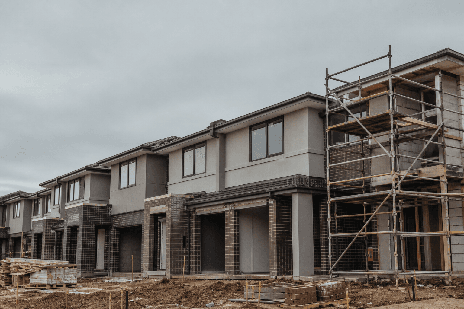 Row of modern townhouses under construction with brick and render finishes